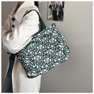 Detail of green floral canvas tote bag with multi-pocket design and adjustable strap