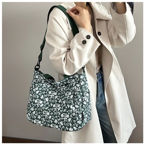 Detail of dark green floral tote bag with white patterns and a wide shoulder strap