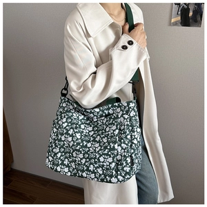 Model showing large dark green canvas tote bag with white floral pattern and wide strap