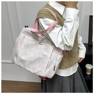 Close-up of pink floral canvas tote bag featuring front snap pocket and reinforced straps
