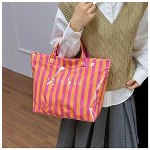 Détail du sac cabas à rayures colorées avec texte blanc porté par un mannequin étudiant