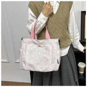 Detail of pink floral tote bag showing side pocket, canvas fabric, and strap attachment
