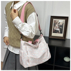 Detailed view of pink floral canvas tote with wide adjustable strap and side pockets