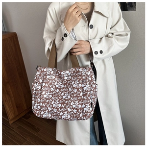 Floral canvas tote bag featuring brown fabric straps and elegant daisy pattern detail