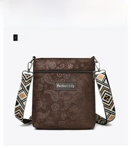 Detail of dark brown paisley embossed crossbody bag with geometric woven strap