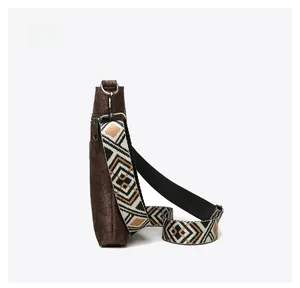 Side view of brown embossed crossbody bag with ethnic geometric woven shoulder strap
