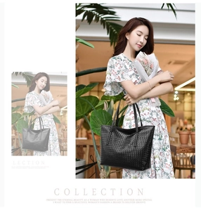 Close-up of woven texture on a large black tote bag with elegant handheld strap design