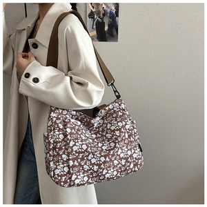 Floral tote bag detail featuring brown canvas, white flower pattern and wide shoulder strap