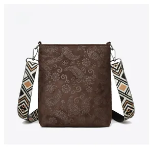 Close-up of brown paisley embossed crossbody bag with bohemian patterned wide strap