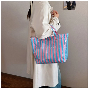 Gros plan d'un mannequin portant un sac fourre-tout rayé rose et bleu avec texte