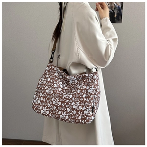 Detail of floral print tote bag featuring brown nylon shoulder strap and plastic buckles