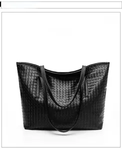 Front view of large black woven tote bag with dual shoulder straps and textured leather finish