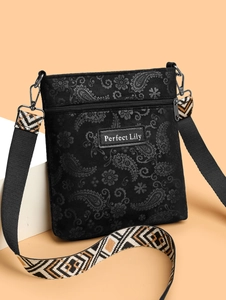 Detail of black paisley embossed crossbody bag with geometric pattern wide fabric strap