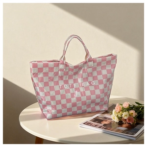 Pink and white checkered tote bag with printed text on a modern table next to flowers