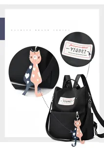 Détail du sac à dos en nylon noir imperméable avec pendentif chat et écusson