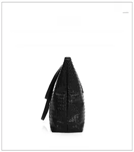 Side view of black woven tote bag with smooth synthetic leather straps and trapezoid shape