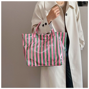 Détail du sac cabas à rayures roses et vertes tenu par un mannequin en trench-coat