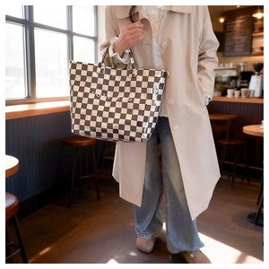 Close-up of stylish brown and white checkered tote bag featuring TOTE BAG text print