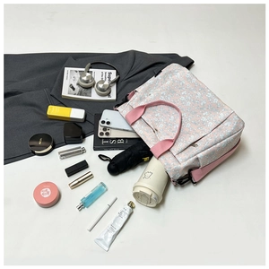 Flat lay of pink floral canvas tote bag with daily essentials showing large storage capacity