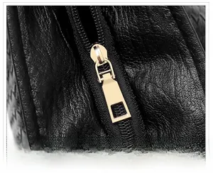 Close-up of golden metal zipper and smooth black lychee leather texture on tote bag