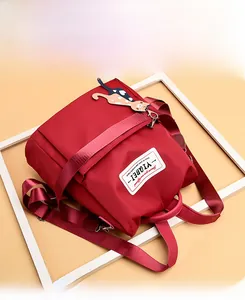 Détail du sac à dos en nylon rouge imperméable avec sangles et pendentif chat