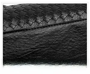 Detailed close-up of black woven leather texture and precision stitching on the tote bag