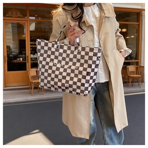 Outdoor shot of a stylish checkered tote bag held by a model in a beige trench coat
