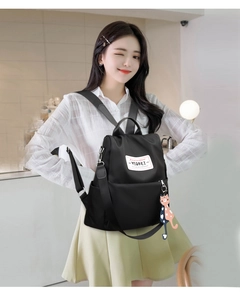 Détail d'un sac à dos en nylon noir avec logo de marque et pendentifs en forme de chat