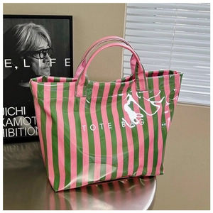 Détail du sac cabas rayé rose et vert brillant avec texte blanc sur une table