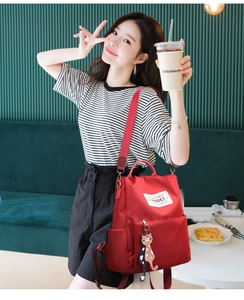 Détail d'un sac à dos rouge en tissu oxford avec porte-clé chat dans un décor de café