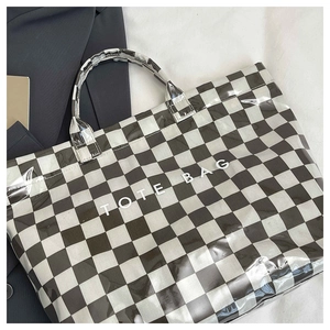 Detail of checkered tote bag in gloss finish featuring TOTE BAG text on fabric background