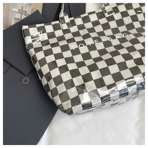 Detail of checkered tote bag with TOTE BAG print on glossy patent leather surface