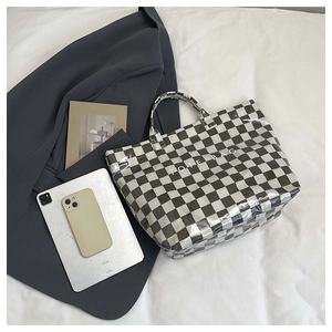 Detail of checkered tote bag with TOTE BAG print in a modern office setup
