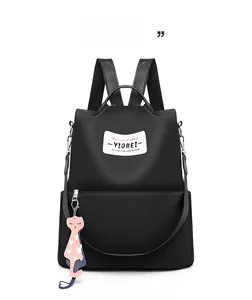 Détail du sac à dos en nylon noir avec étiquette de marque et charm chat et cœur