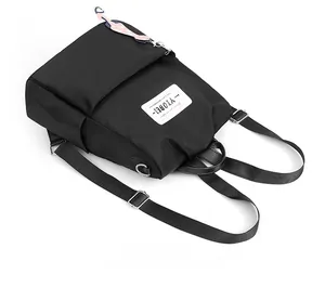 Détail du sac à dos oxford noir avec pendentif chat rose et boucles en métal réglables