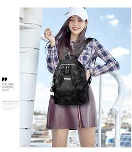 Détail d'un sac à dos noir imperméable à texture géométrique avec pendentif poupée
