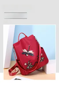 Close-up of 3D embroidered dragonfly and floral patterns with pearl accents on red backpack