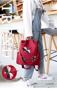 Detail of red backpack featuring 3D embroidered dragonfly with sequins and floral patterns