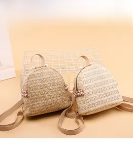 Dettaglio di mini zaini in paglia intrecciata con perle e ciondoli floreali