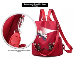 Detail showing the detachable red fabric shoulder strap and metal hook of the backpack