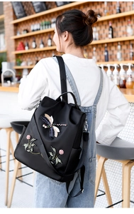 Close-up of 3D dragonfly embroidery and bead details on women's black Oxford backpack