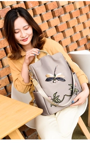Detail of embroidered dragonfly on grey oxford fabric backpack in a lifestyle setting