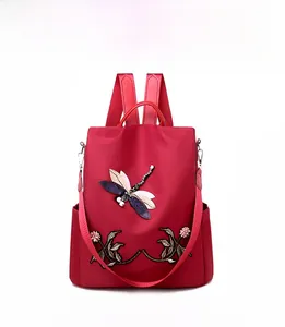 Detailed close-up of 3D dragonfly embroidery on a red waterproof nylon backpack