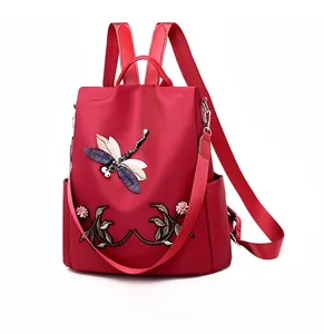 Detail of red oxford backpack featuring 3D embroidered dragonfly and floral patterns