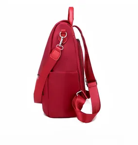 Side view of red oxford fabric backpack with silver hardware and adjustable straps