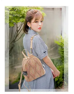 Detail of woven straw backpack featuring pearl decor, tassels and canvas straps