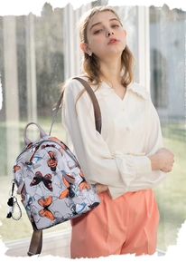 Detail of light gray water-resistant nylon backpack with vibrant butterfly print and side charm