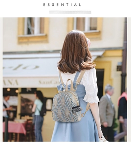 Detail of woven straw mini backpack with white pearl decor and grey tassel accents