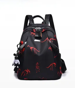 Front view of black dinosaur print backpack with stylish bear charm and silver zippers