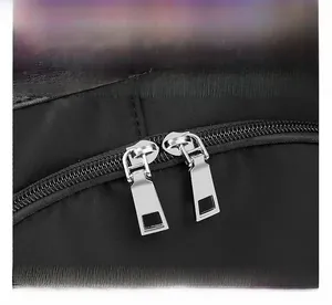 Détail des fermetures éclair argentées sur un sac à dos en tissu Oxford noir résistant